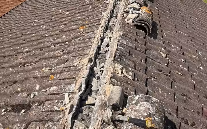 Old mortar-bedded ridge tiles with cracked and missing pointing
